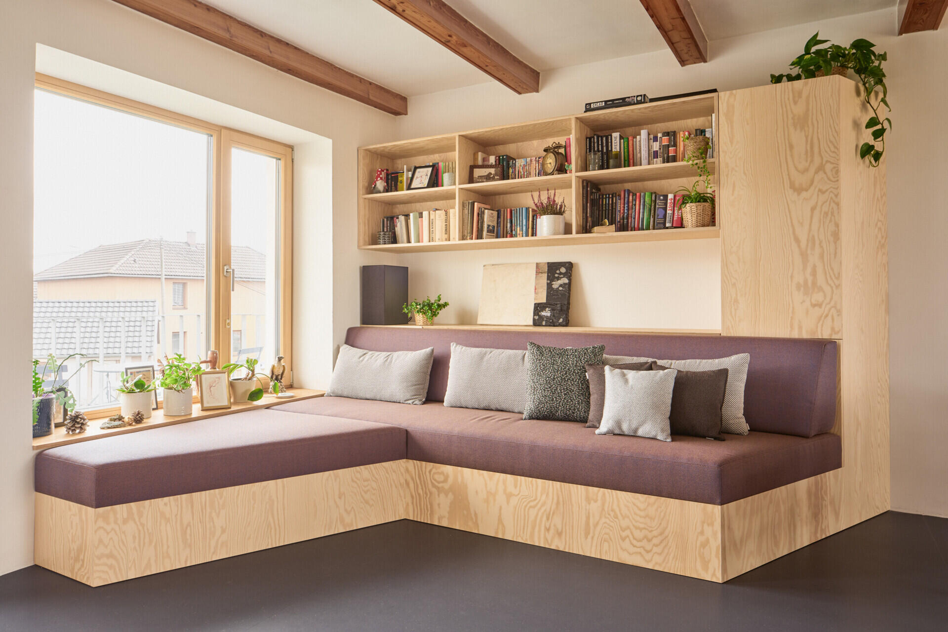 Custom pine plywood furniture transforms part of this renovated Czech home by Facha architekti into a relaxed secondary living space, with built-in seating, bookshelves and storage making efficient use of the compact interior.