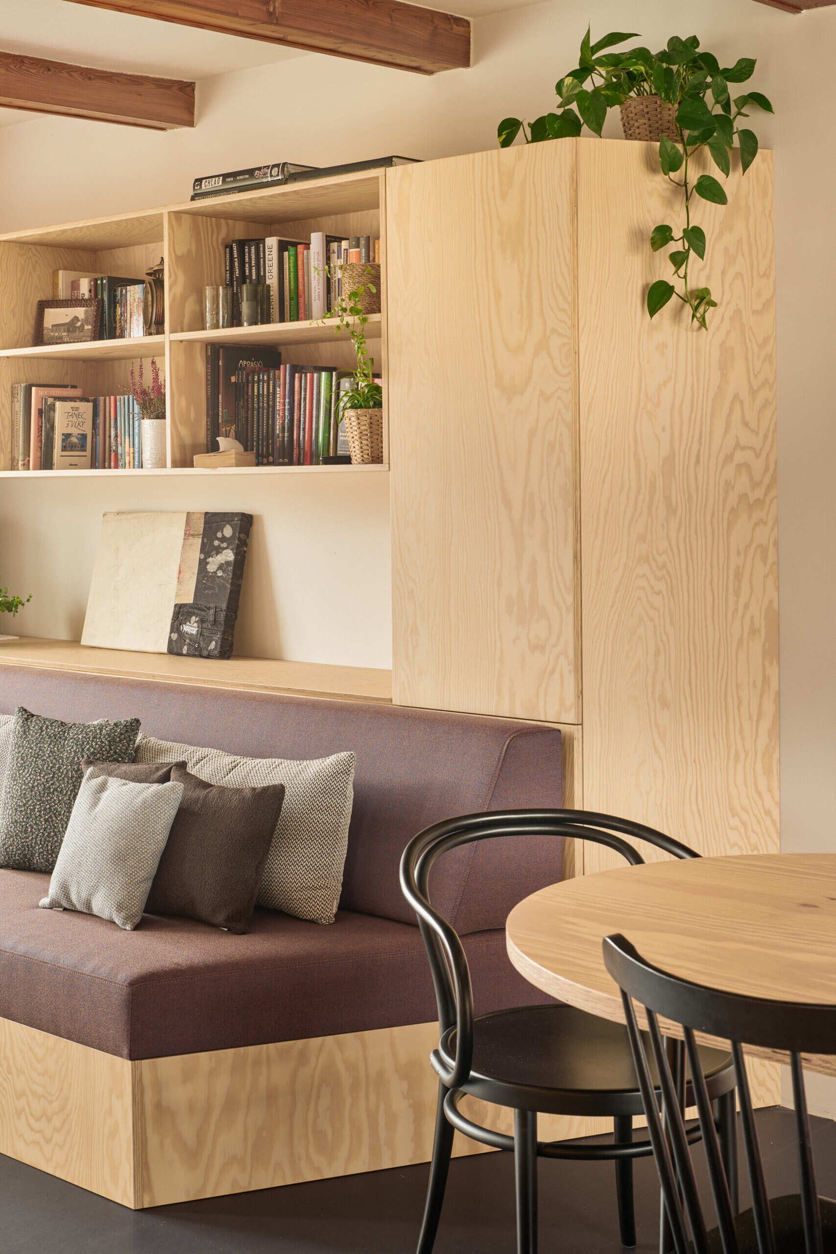 Custom pine plywood furniture transforms part of this renovated Czech home by Facha architekti into a relaxed secondary living space, with built-in seating, bookshelves and storage making efficient use of the compact interior.
