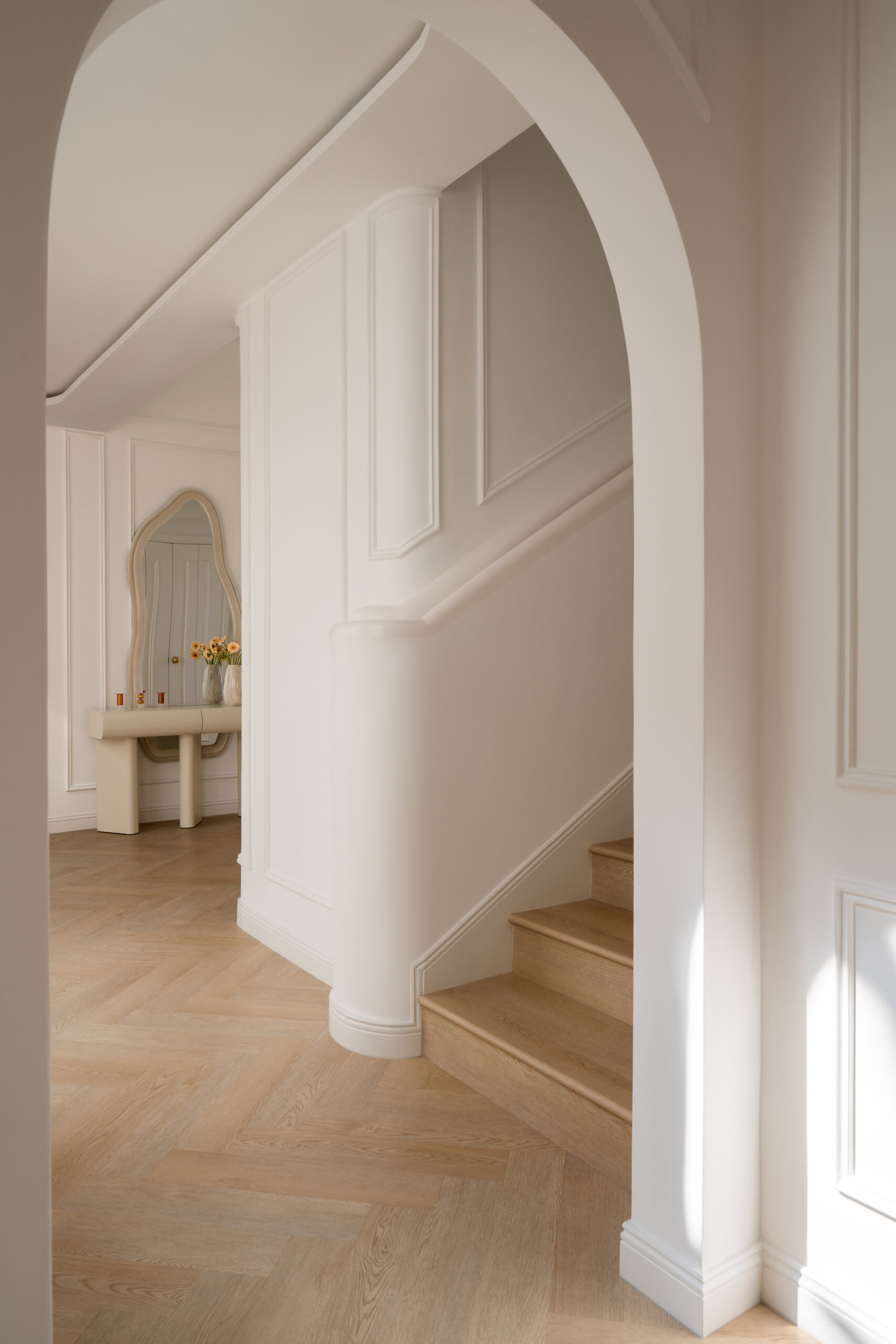 A beautifully renovated staircase inside The White Arcade in Dubai. D’Ora Tokai Designs transformed the original angular staircase with curved architectural details, oak steps, elegant white wall panelling, and a sculptural upper landing overlooking the central courtyard.