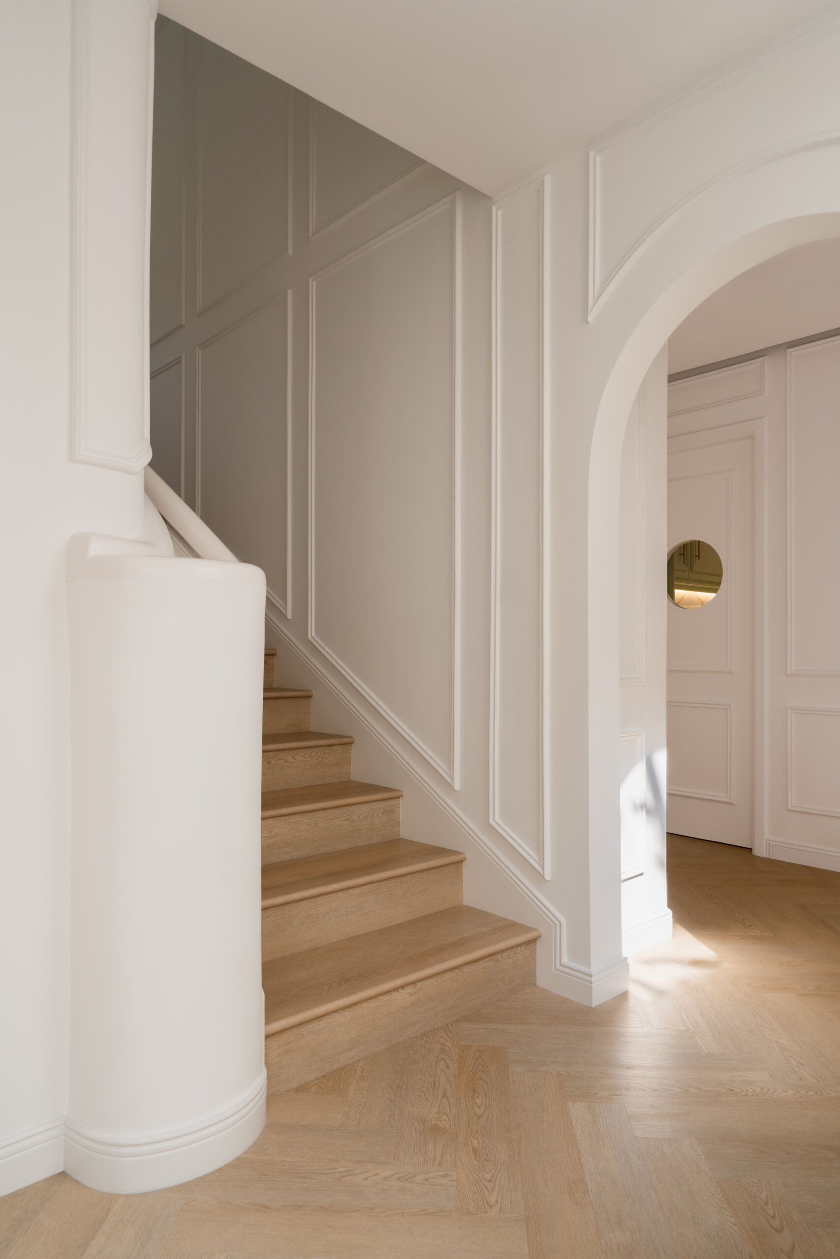 A beautifully renovated staircase inside The White Arcade in Dubai. D’Ora Tokai Designs transformed the original angular staircase with curved architectural details, oak steps, elegant white wall panelling, and a sculptural upper landing overlooking the central courtyard.