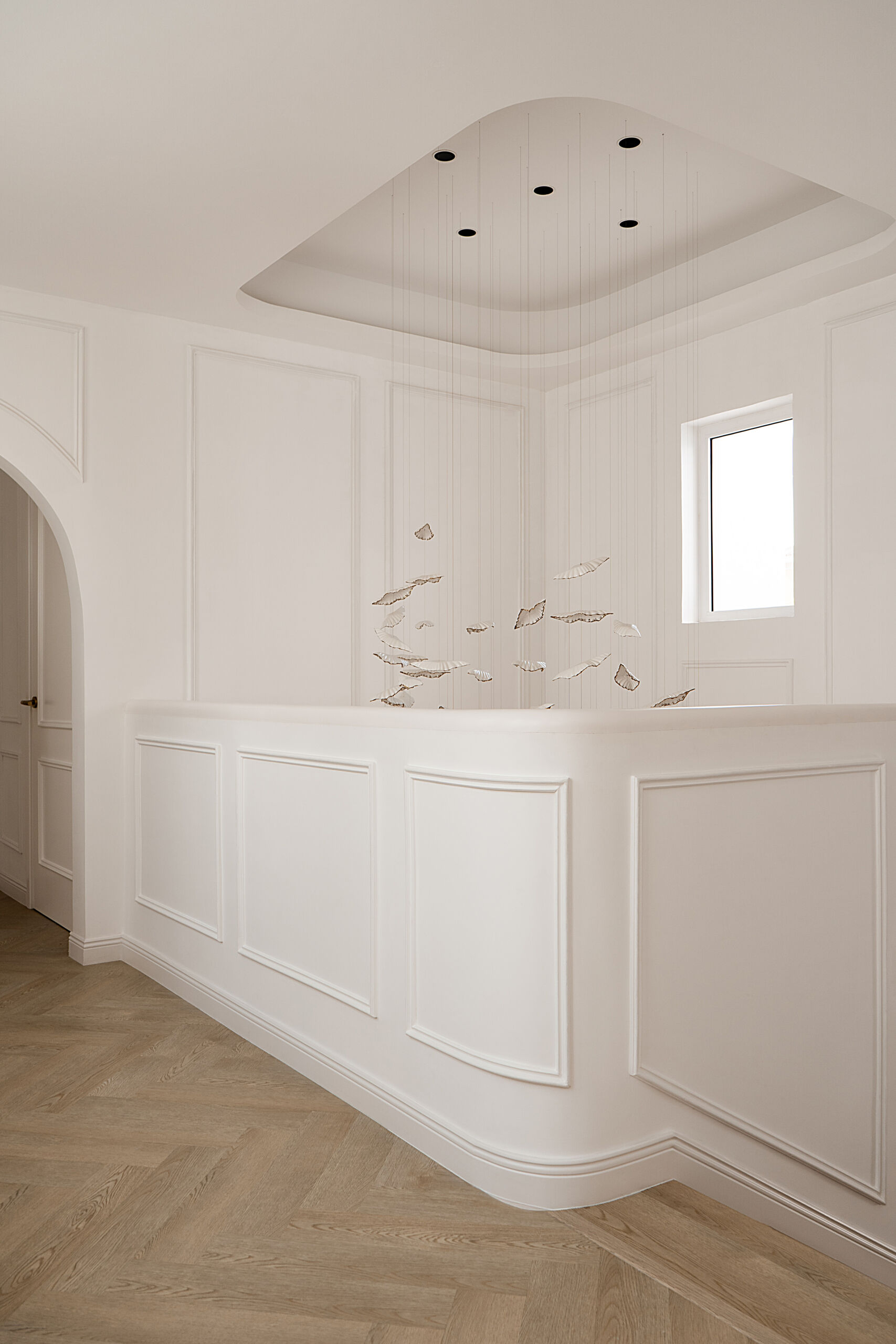 A beautifully renovated staircase inside The White Arcade in Dubai. D’Ora Tokai Designs transformed the original angular staircase with curved architectural details, oak steps, elegant white wall panelling, and a sculptural upper landing overlooking the central courtyard.